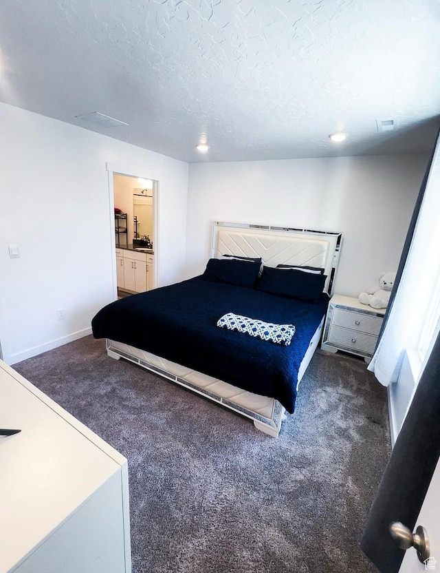 carpeted bedroom with connected bathroom and a textured ceiling