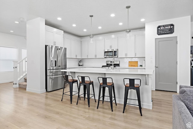 11283 S Willow Walk Dr W, South Jordan, UT 84009 - kitchen with appliances with stainless steel finishes, light countertops, backsplash, a kitchen bar, and recessed lighting