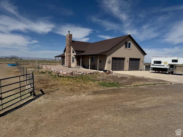 view of front of house featuring a chimney, concrete driveway, fence, a garage, and stucco siding