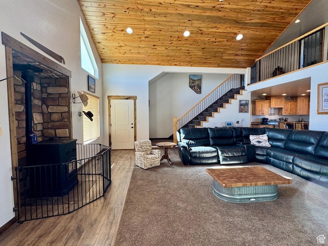 living area featuring stairway, wood finished floors, a wood stove, wood ceiling, and high vaulted ceiling