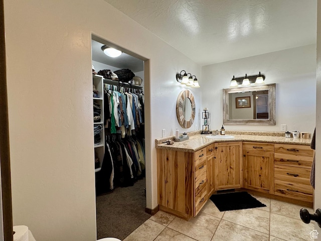 bathroom featuring a spacious closet, tile patterned flooring, and vanity
