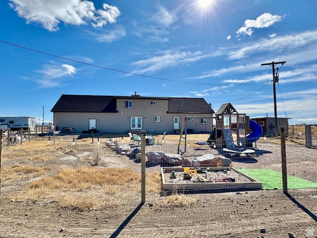 back of house with a garden and a playground