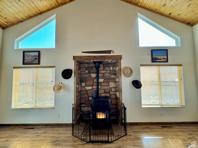 details featuring visible vents, baseboards, wood finished floors, wooden ceiling, and a wood stove