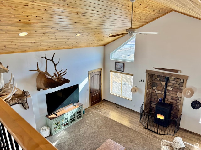 living area with high vaulted ceiling, wood finished floors, ceiling fan, a wood stove, and wooden ceiling