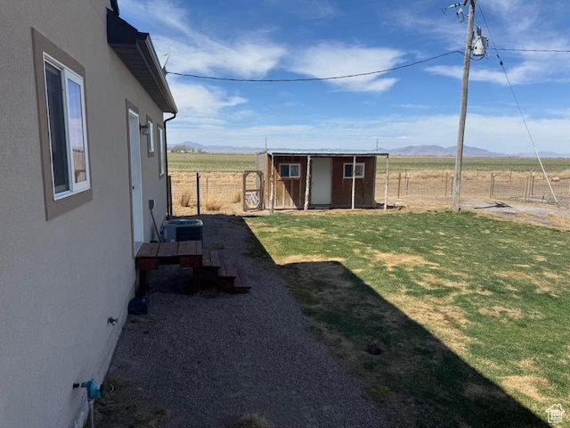 view of yard featuring an outdoor structure, a mountain view, fence, and a shed
