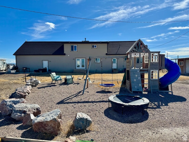 back of house featuring a playground, a shingled roof, and an outdoor fire pit