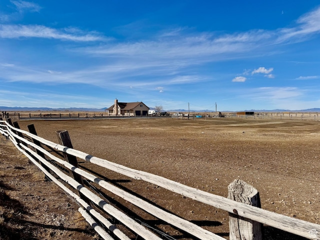 view of yard featuring fence, a rural view, and a mountain view