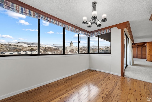 241 N Vine St W Unit 1101E, Salt Lake City, UT 84103 - spare room featuring wood-type flooring, a mountain view, a textured ceiling, and a notable chandelier