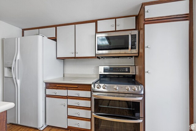 241 N Vine St W Unit 1101E, Salt Lake City, UT 84103 - kitchen with appliances with stainless steel finishes, white cabinets, and light hardwood / wood-style flooring