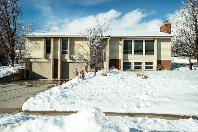 view of front facade featuring brick siding, driveway, and a chimney