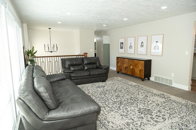 carpeted living room with a notable chandelier, recessed lighting, visible vents, a textured ceiling, and baseboards