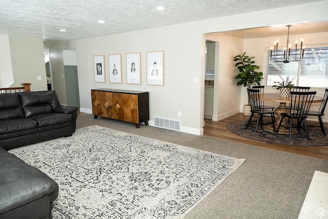 living area featuring baseboards, visible vents, a textured ceiling, a notable chandelier, and recessed lighting