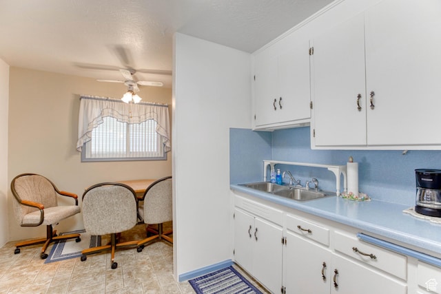 kitchen featuring tasteful backsplash, sink, white cabinets, ceiling fan, and a textured ceiling