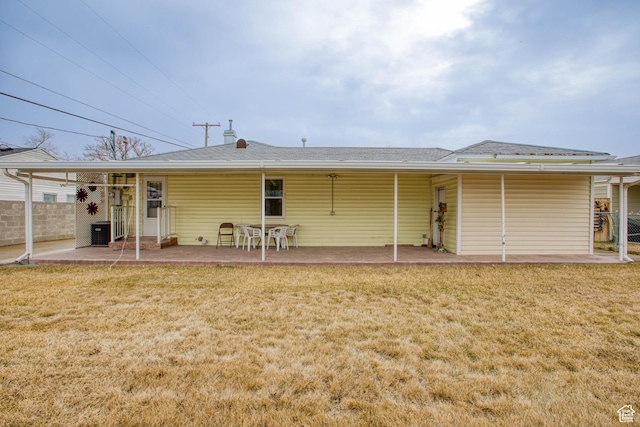 rear view of house featuring a patio, central AC, and a lawn