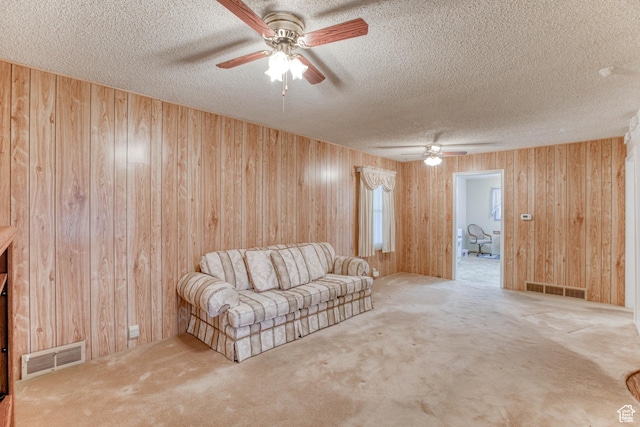 unfurnished living room with ceiling fan, carpet flooring, wooden walls, and a textured ceiling