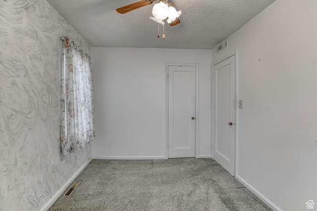 spare room featuring ceiling fan, light colored carpet, and a textured ceiling