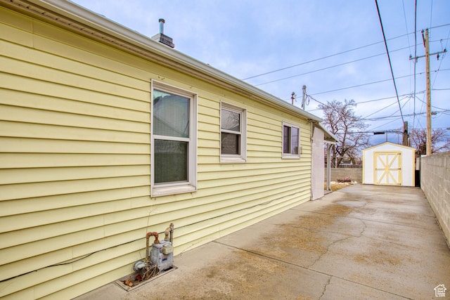 view of side of home featuring a patio area and a shed
