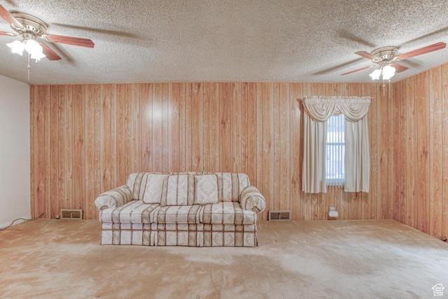 unfurnished room featuring ceiling fan, wooden walls, a textured ceiling, and carpet flooring