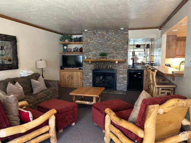 living room with a fireplace, ornamental molding, a textured ceiling, and carpet flooring