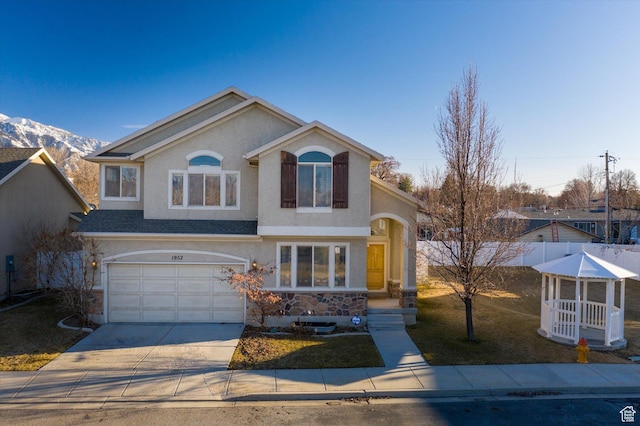 traditional-style home featuring a front yard, fence, stucco siding, concrete driveway, and a garage