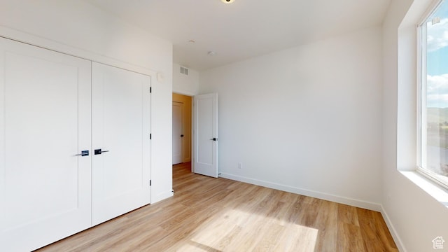 1266 S Sawmill Blvd Unit 3-303, Heber City, UT 84032 - unfurnished bedroom featuring multiple windows, a closet, and light hardwood / wood-style floors
