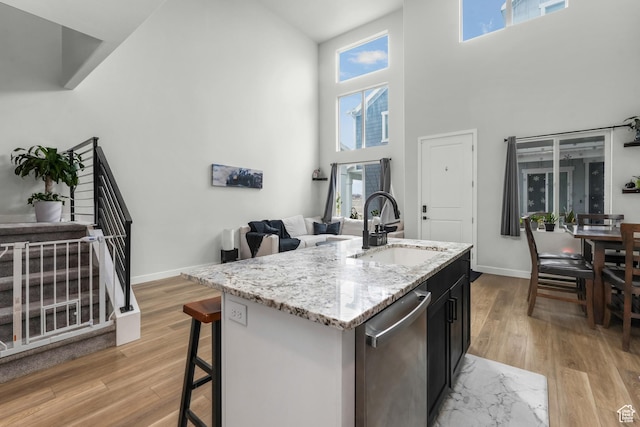 kitchen with a center island with sink, sink, dishwasher, and light wood-type flooring