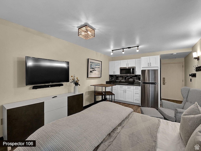 bedroom with hardwood / wood-style flooring and stainless steel fridge