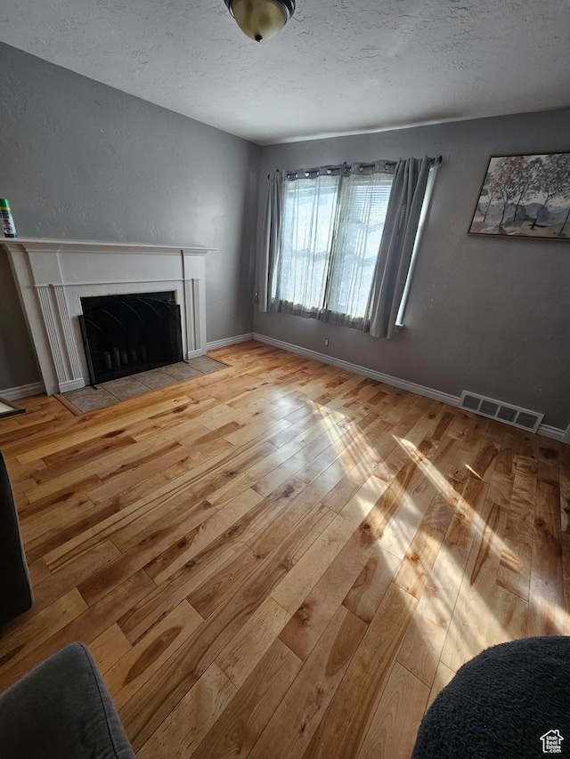 1060 E 30th S, Ogden, UT 84403 - living room featuring visible vents, baseboards, a fireplace with flush hearth, hardwood / wood-style flooring, and a textured ceiling