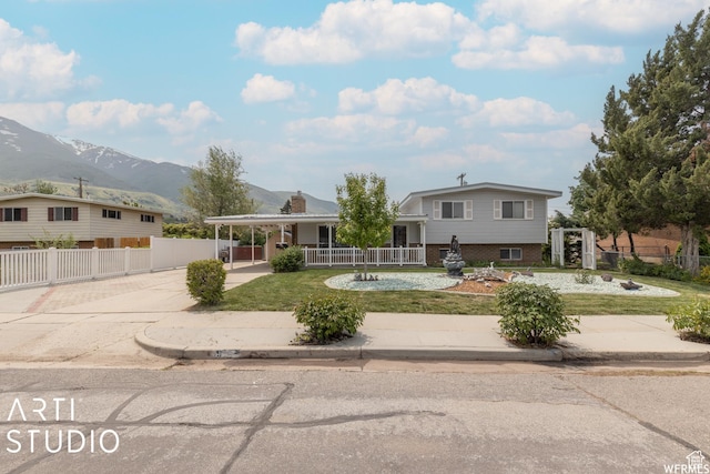 view of front of house with driveway, fence, a mountain view, a front yard, and brick siding