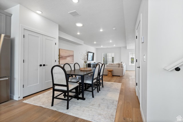 dining room featuring light hardwood / wood-style floors and a textured ceiling