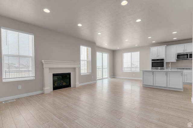 1282 E Clipper Peaks, Eagle Mountain, UT 84005 - unfurnished living room with light hardwood / wood-style floors and a textured ceiling