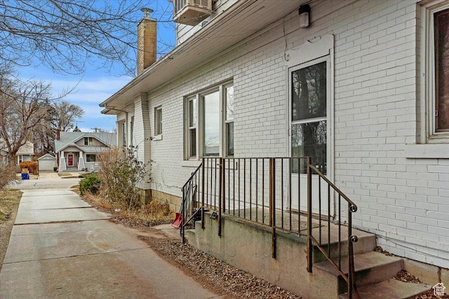 view of side of home with a chimney and brick siding