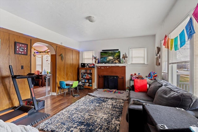living room featuring arched walkways, wood finished floors, and a fireplace