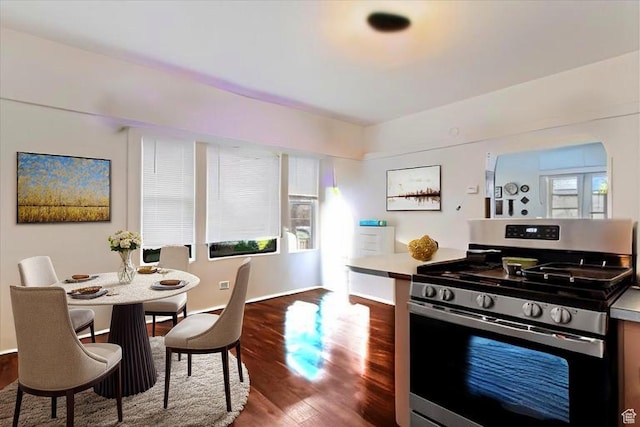 kitchen with stainless steel range with gas cooktop, baseboards, and dark wood-type flooring