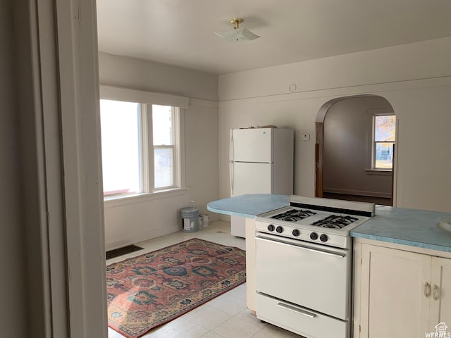 2424 S Jackson Ave E, Ogden, UT 84401 - kitchen featuring white appliances, arched walkways, white cabinetry, and light countertops