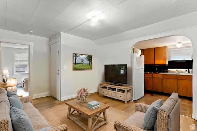 living area with light wood finished floors, baseboards, and arched walkways