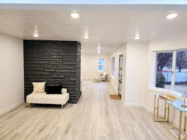 living area featuring a textured ceiling, baseboards, wood finished floors, and recessed lighting