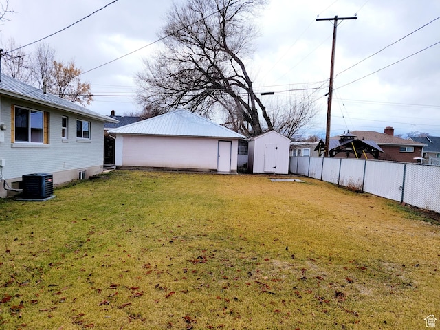 view of yard featuring an outbuilding, fence, a shed, and central AC unit