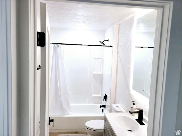 full bath with a textured wall, toilet, shower / tub combo with curtain, a textured ceiling, and vanity