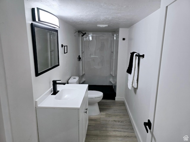 full bath featuring a stall shower, toilet, wood finished floors, a textured ceiling, and vanity