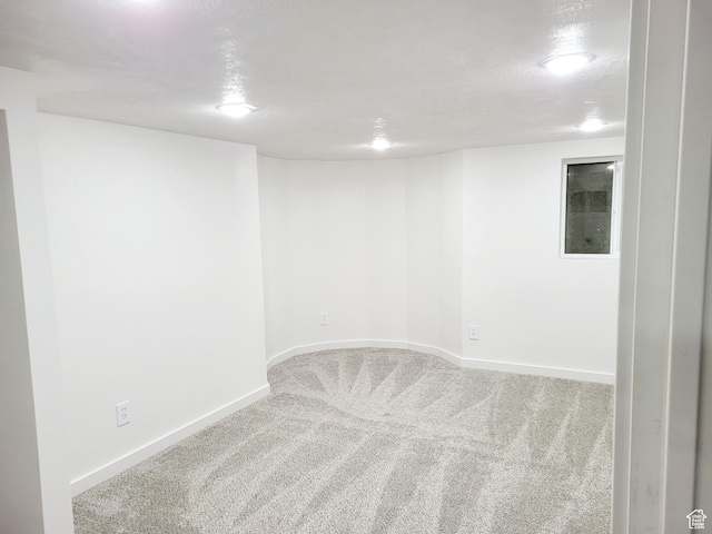 carpeted spare room featuring a textured ceiling and baseboards