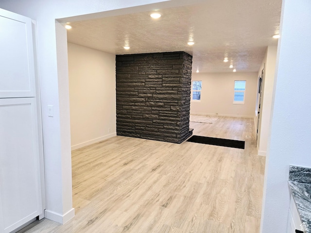 interior space featuring a textured ceiling, recessed lighting, wood finished floors, and baseboards