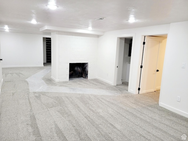 finished below grade area featuring a fireplace, carpet flooring, visible vents, and baseboards