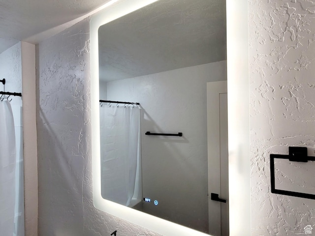 bathroom featuring a shower with shower curtain and a textured wall