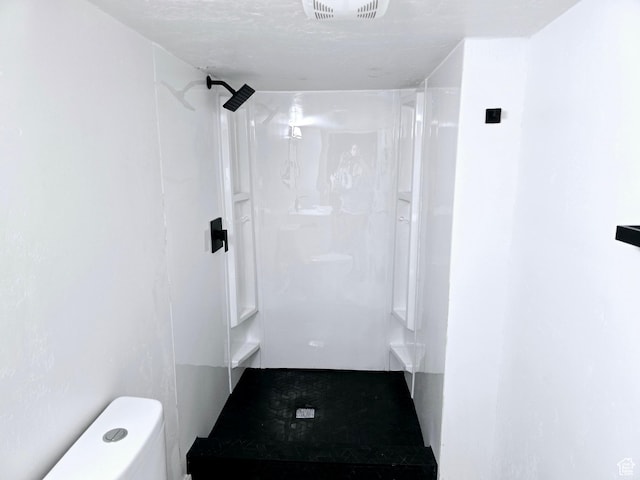 bathroom featuring toilet, a shower stall, and visible vents