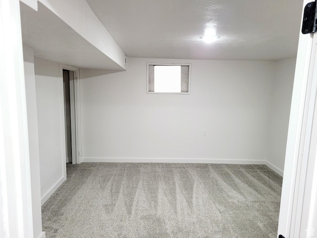 below grade area featuring carpet floors, a textured ceiling, and baseboards