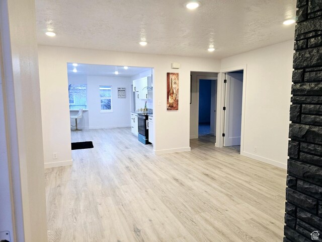 unfurnished living room with a textured ceiling, baseboards, and wood finished floors
