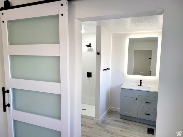 bathroom featuring a textured ceiling, wood finished floors, visible vents, vanity, and a stall shower