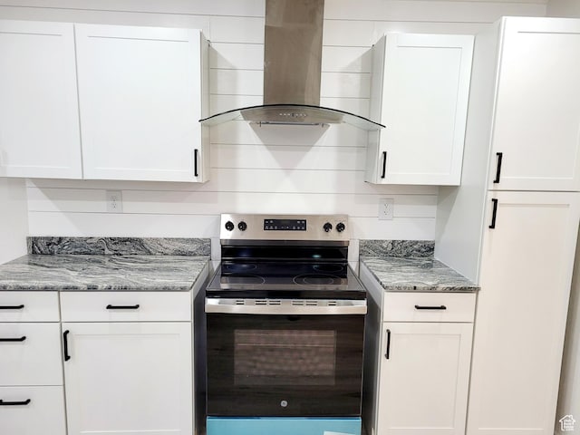 kitchen featuring light stone countertops, wall chimney range hood, stainless steel range with electric stovetop, and white cabinets