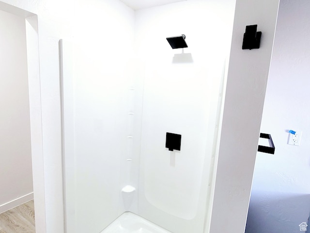 bathroom featuring a shower, baseboards, and wood finished floors